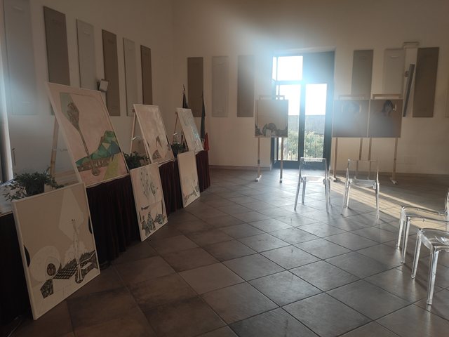 Una fila di opere su cavalletti lungo la parete della sala
